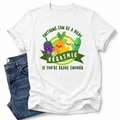 A white graphic t-shirt featuring cartoon vegetables and the text 'ANYTHING CAN BE A DILDO, IF YOU'RE BRAVE ENOUGH', styled flat-lay with blue jeans on a white background. Gra your tee from Coffee and Moo NZ.