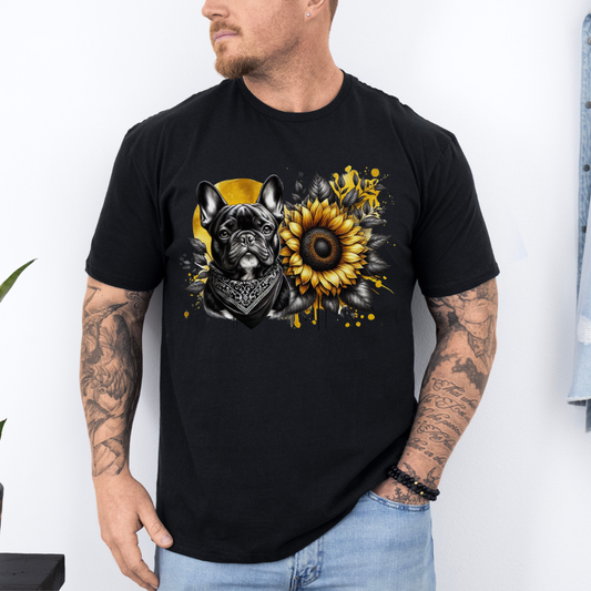 A man wearing a black graphic t-shirt featuring a French Bulldog and a sunflower design, paired with light blue jeans against a white wall. Grab your tee from Coffee and Moo NZ.