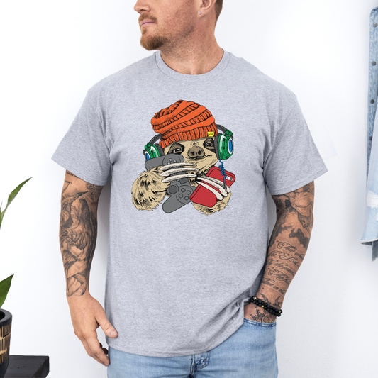 Male wearing a grey graphic T-shirt featuring a colorful cartoon sloth wearing an orange knit beanie, green headphones, while holding a red phone and grey controller. Grab your tee from Coffee and Moo NZ.