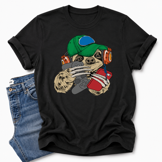 A black short-sleeve t-shirt with a colorful graphic of a sloth wearing a green cap, orange headphones, while holding a grey controller and red phone. The shirt is styled flat-lay with a pair of blue jeans on a light gray background. Grab your tee from Coffee and Moo NZ.