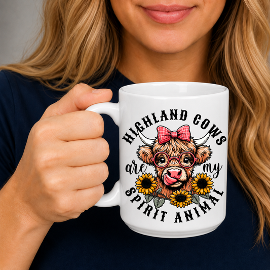 A person holding a white ceramic mug with a graphic of a Highland cow wearing a pink bow, surrounded by sunflowers and the text 'HIGHLAND COWS are my SPIRIT ANIMAL'. from Coffee and Moo NZ.