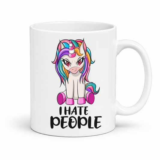 A white ceramic mug featuring a cartoon illustration of a white unicorn with a vibrant rainbow mane and tail, sitting above the text 'I HATE PEOPLE' in black. The mug is shown on a clean white background with a soft shadow. From Coffee and Moo NZ.