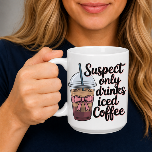 A woman holding a white ceramic mug with a humorous graphic that reads 'Suspect only drinks iced Coffee' next to an illustration of an iced coffee drink with a pink bow. From Coffee and Moo NZ.