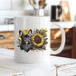 A white ceramic coffee mug with a graphic print of a French bulldog wearing a bandana next to a large sunflower, set on a rustic white wooden bench in a blurred kitchen background. Grab your frenchie mug from Coffee and Moo NZ
