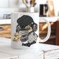 A white ceramic mug featuring a cartoon illustration of a sloth wearing a black knit beanie, over-ear headphones, and holding a cup with the word 'TEARS' on it and a diary, shown against a plain white background. Grab yours from Coffee and Moo NZ. The mug is photographed on a rustic white wooden surface with a blurred kitchen background.