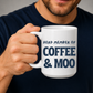 A man in a navy blue t-shirt holds a white ceramic mug with the text 'HERD MEMBER OF COFFEE & MOO' printed in navy blue lettering. Grab your mug from Coffee and Moo NZ.