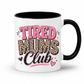 A white ceramic mug with a black interior and handle, featuring a graphic design that reads 'TIRED MUMS Club' in pink and leopard print lettering. Grab your mug from Coffee and Moo NZ.