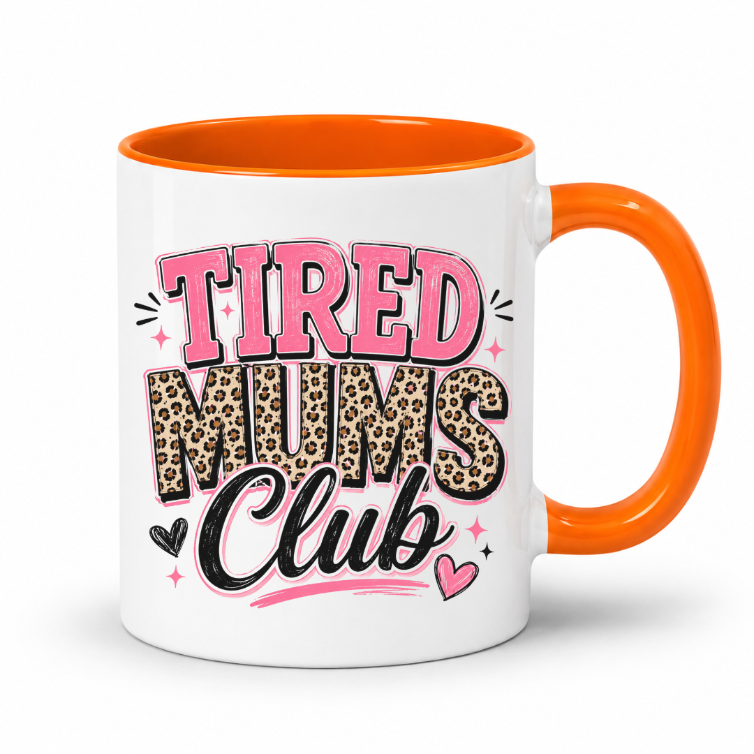 A white ceramic mug with a bright orange handle and interior, featuring the text 'TIRED MUMS Club' in pink, leopard print, and black lettering on the front. Grab your mug from Coffee and Moo NZ.
