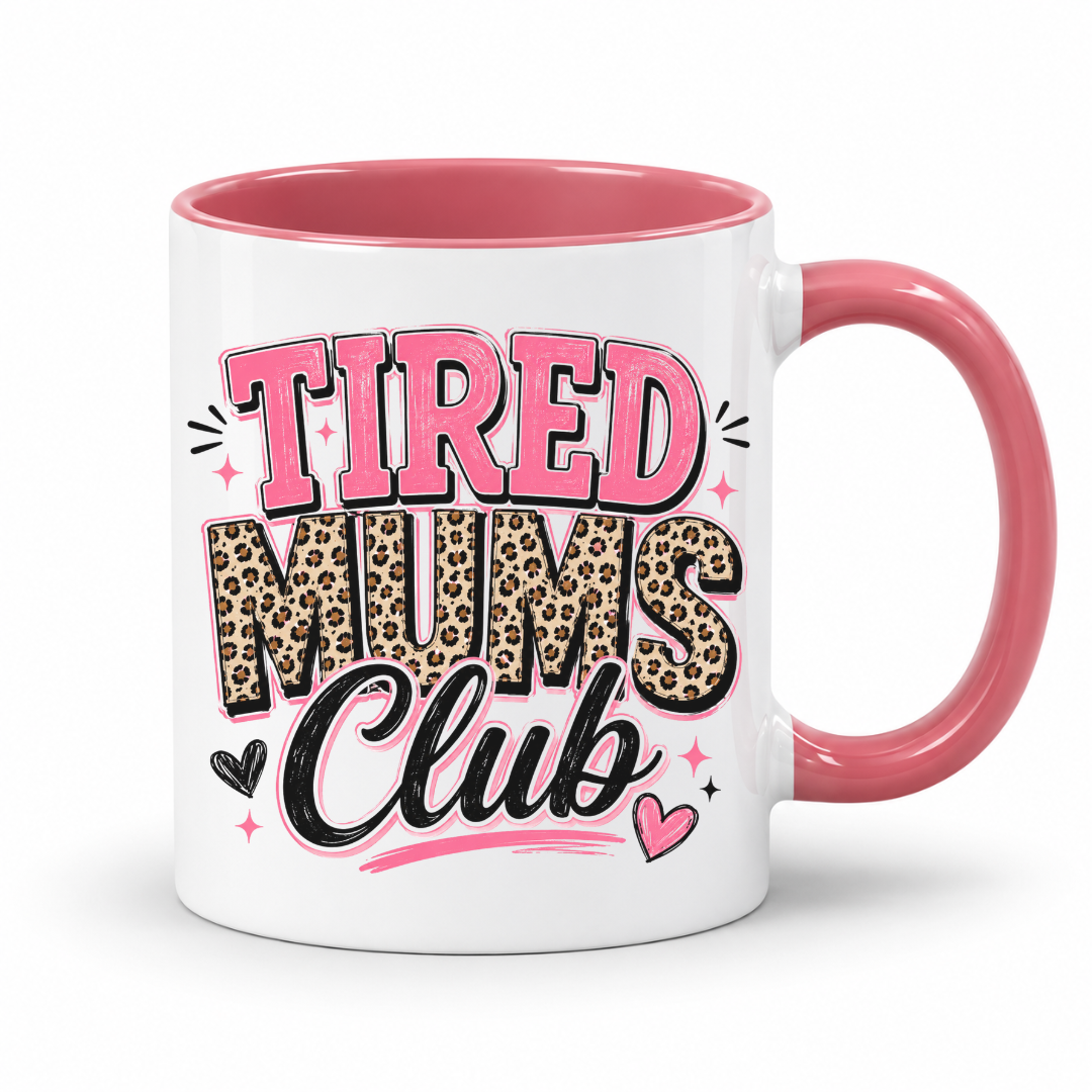 A white ceramic mug with a pink interior and handle, featuring the text 'TIRED MUMS Club' in pink, leopard print, and black lettering on the front. Grab your mug from Coffee and Moo NZ.