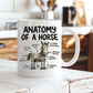 A white ceramic mug with a humorous 'Anatomy of a Horse' graphic, sitting on a rustic white wooden surface with a blurred kitchen background. From Coffee and Moo NZ.