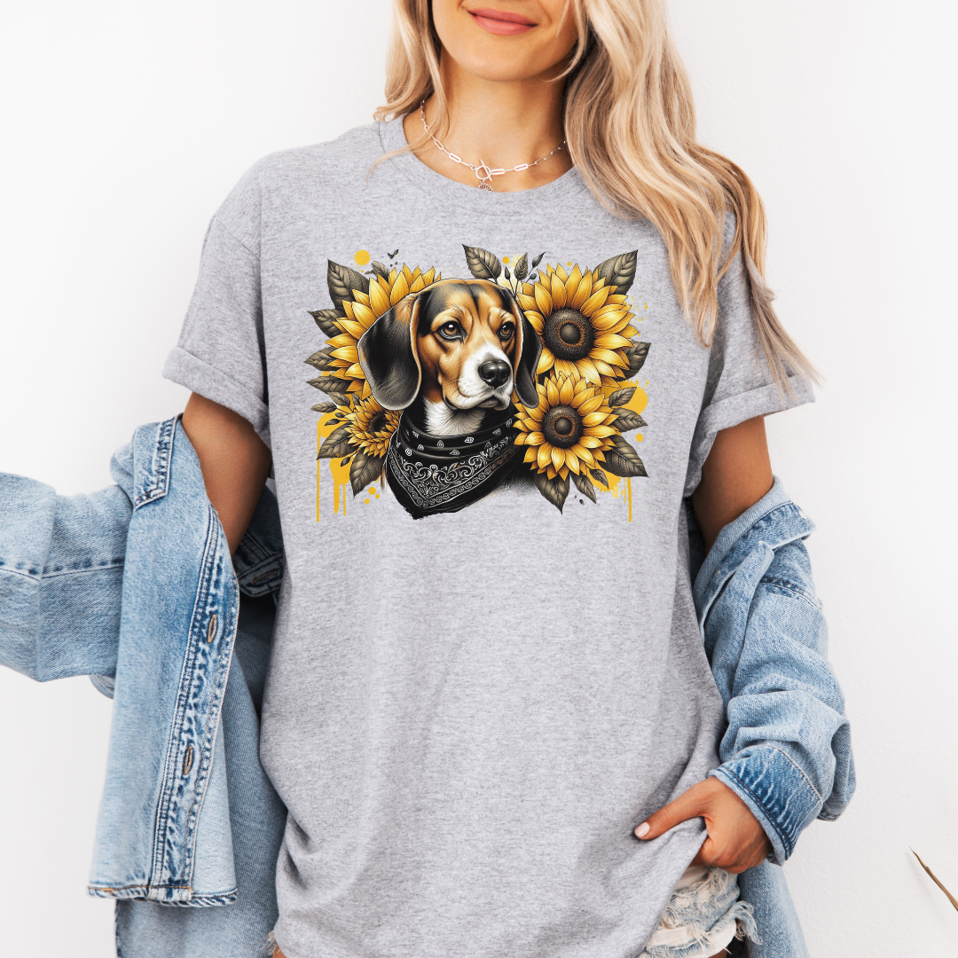A woman wearing agrey t-shirt with a graphic print of a beagle dog surrounded by yellow sunflowers, styled with an open light blue denim jacket. Grab your tee from Coffee and Moo.