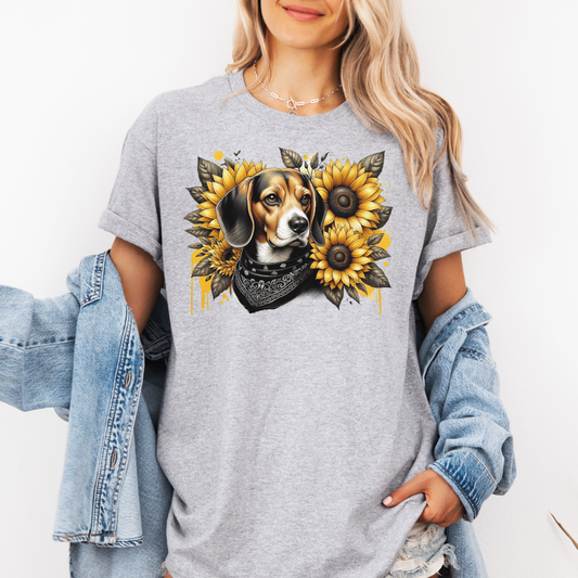 A woman wearing agrey t-shirt with a graphic print of a beagle dog surrounded by yellow sunflowers, styled with an open light blue denim jacket. Grab your tee from Coffee and Moo.