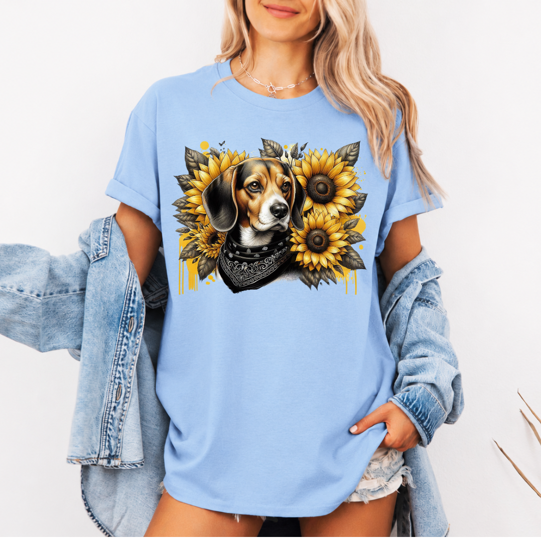 A woman wearing a light blue graphic t-shirt with a beagle dog and sunflower design, styled with an open light-wash denim jacket against a plain white background. Grab your tee from Coffee and Moo.
