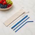 Metallic blue reusable stainless steel straw set with straight, bent and smoothie straws, cleaning brush and drawstring pouch. From Coffee and Moo