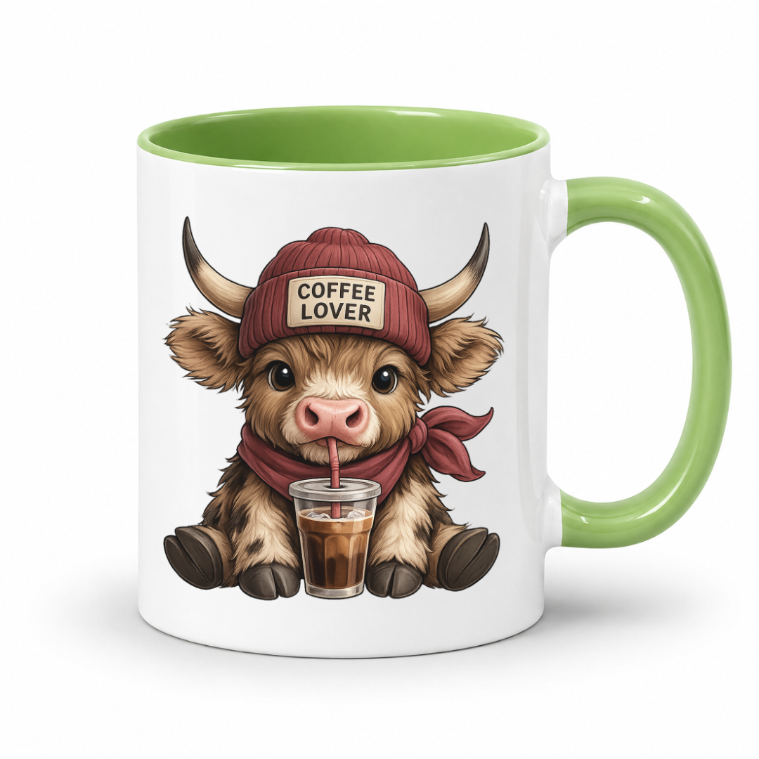 A white ceramic mug with a green interior and handle, featuring a cartoon illustration of a fluffy Highland cow wearing a red beanie that says 'COFFEE LOVER' and drinking from a cup with a straw. from Coffee and Moo.
