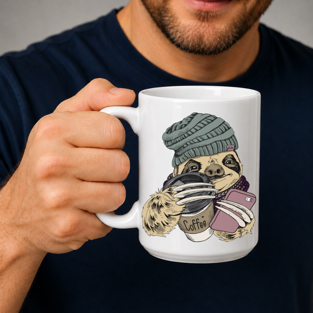 A man in a navy blue shirt holds a white ceramic mug featuring a cute sloth illustration wearing a green beanie and holding a coffee cup and a pink phone. Grab your mug from Coffee and moo NZ.