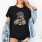 A woman wearing a black oversized graphic t-shirt with a sloth holding a coffee cup and phone, styled with an open light blue denim jacket. Grab your tee from Coffee and Moo NZ.