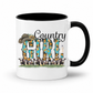 A white ceramic coffee mug with a black interior and handle, featuring a 'Country Girl' graphic design with a cowboy hat, sunflowers, cows, and a milk bottle.  From Coffee and Moo NZ