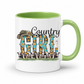 A white ceramic coffee mug with a light green interior and handle, featuring a 'Country Girl' graphic with a cowboy hat, sunflowers, and dairy cows.  From Coffee and Moo NZ