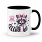 A white ceramic mug with a black interior and black handle, featuring a cute cartoon raccoon wearing heart-shaped glasses and a pink bow, holding a drink, with the text 'CUTE but FERAL' on the front. from Coffee and Moo.