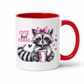 A white ceramic mug with a red interior, red handle, and a printed graphic of a raccoon wearing heart-shaped glasses and a pink bow, holding a drink, with the text 'CUTE but FERAL'. from Coffee and Moo.