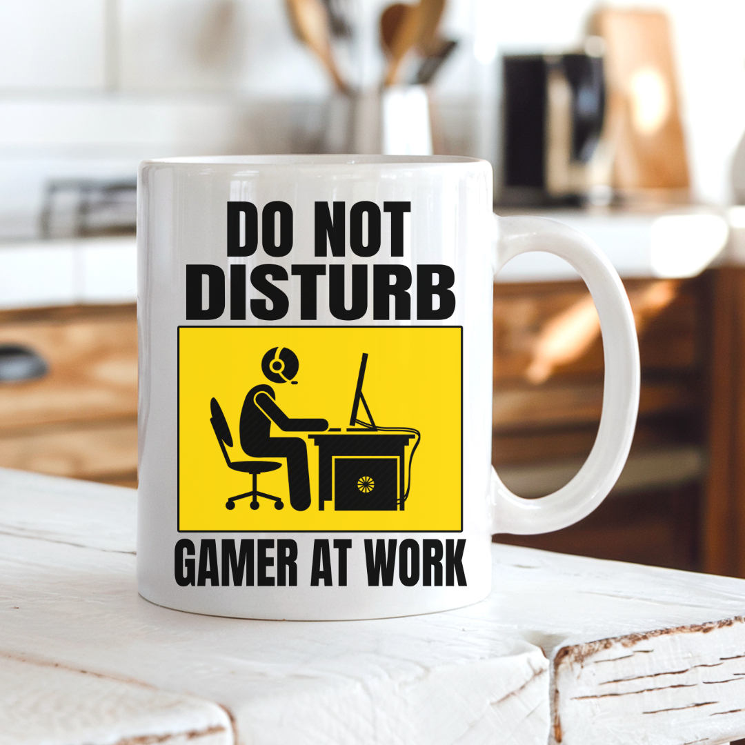 Do Not Disturb Gamer at Work gaming coffee mug on a country kitchen bench, featuring a bold yellow and black gamer warning design, by Coffee and Moo.