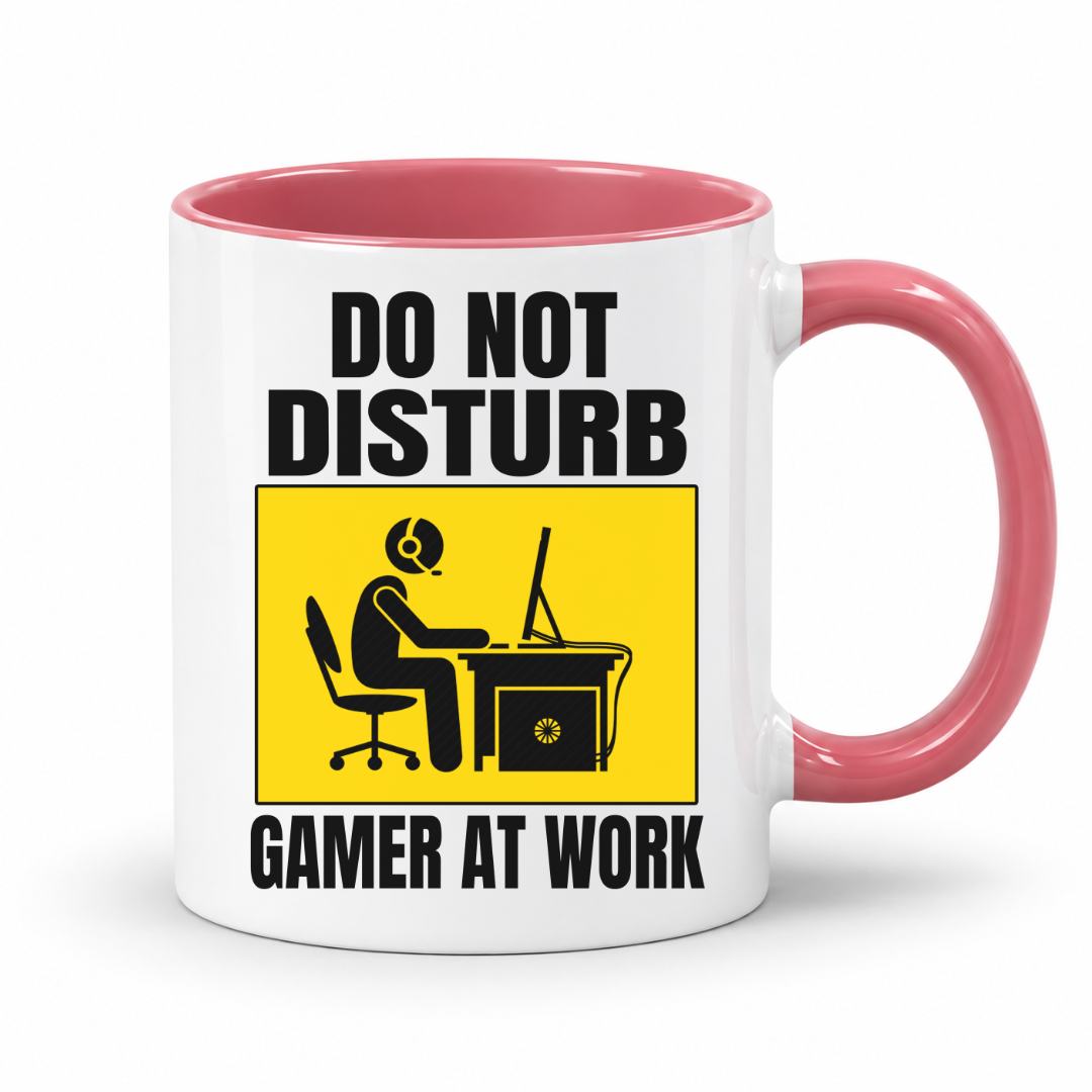 Do Not Disturb Gamer at Work gaming coffee mug featuring pink inner & handle, bold black lettering and a yellow and black graphic of a gamer at a computer, from Coffee and Moo.