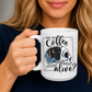 A person holding a white ceramic mug  with a graphic that features a skull with one half showing a starry night sky with a crescent moon and a skeleton holding a coffee, accompanied by the text 'DOES THIS Coffee MAKE ME LOOK alive?'. Grab yours from Coffee and Moo NZ.