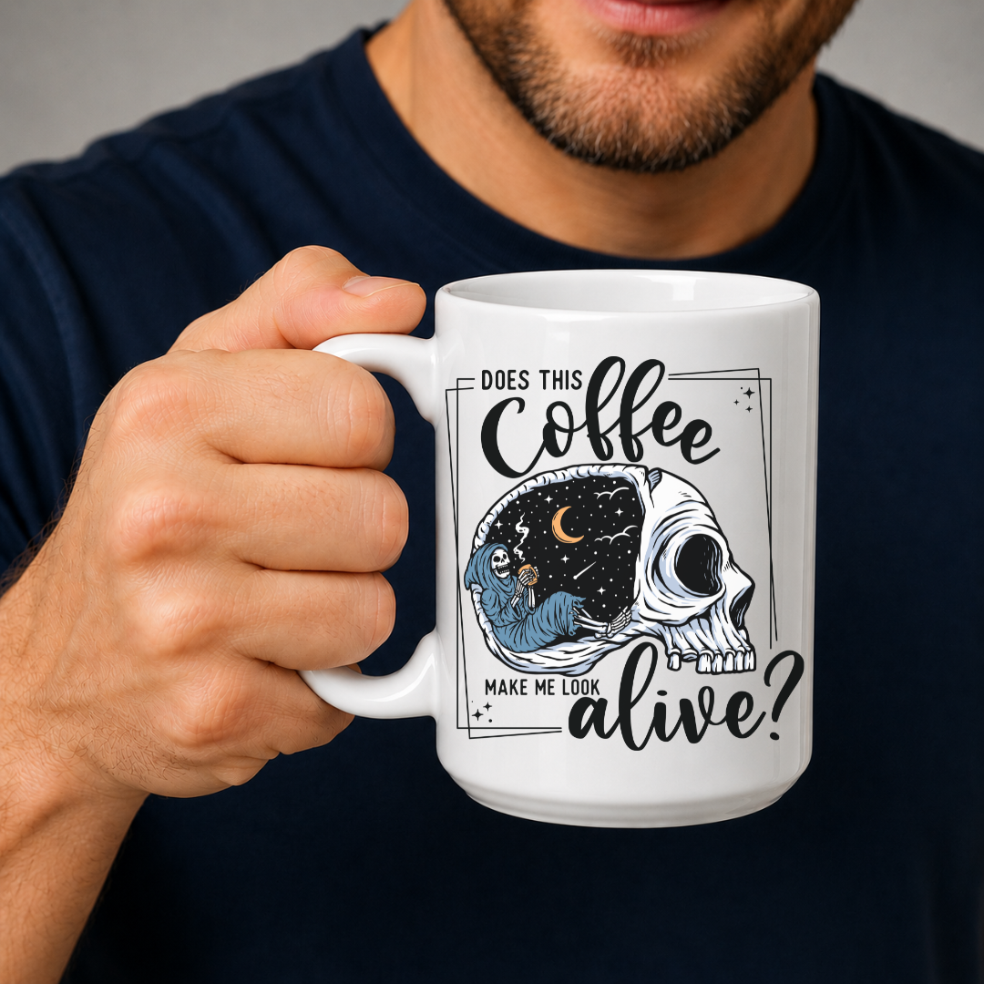 A man in a navy blue t-shirt holds a white ceramic coffee mug with a graphic that features a skull with one half showing a starry night sky with a crescent moon and a skeleton holding a coffee, accompanied by the text 'DOES THIS Coffee MAKE ME LOOK alive?'. Grab yours from Coffee and Moo NZ.
