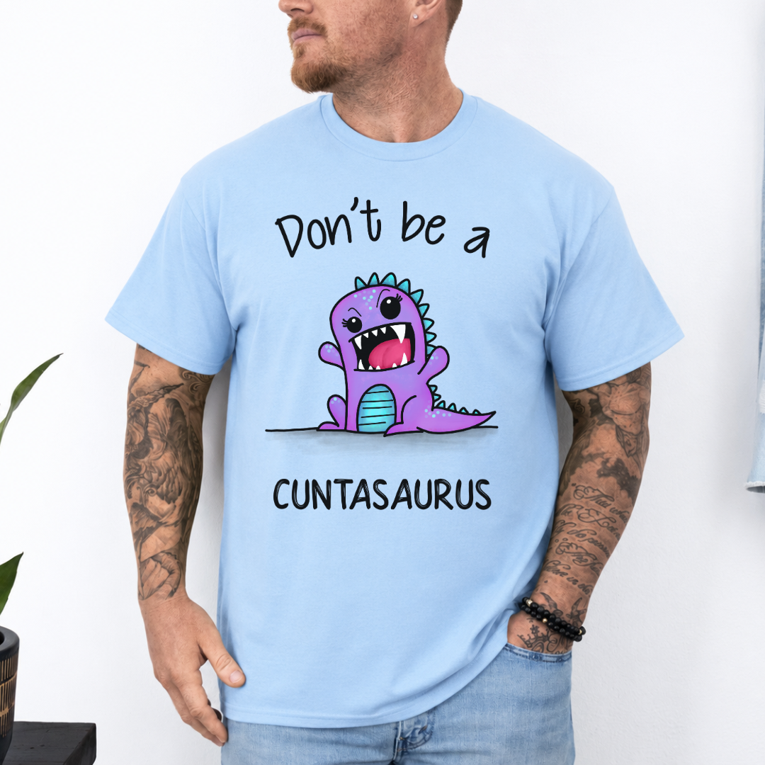 A man wearing a light blue graphic t-shirt with a purple cartoon dinosaur and the text 'Don't be a CUNTASaurus'. Purchase from Coffee and Moo NZ.