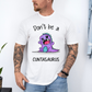 A man wearing a white graphic t-shirt with a cartoon purple dinosaur and the text 'Don't be a CUNTASaurus'. Purchase from Coffee and Moo NZ.