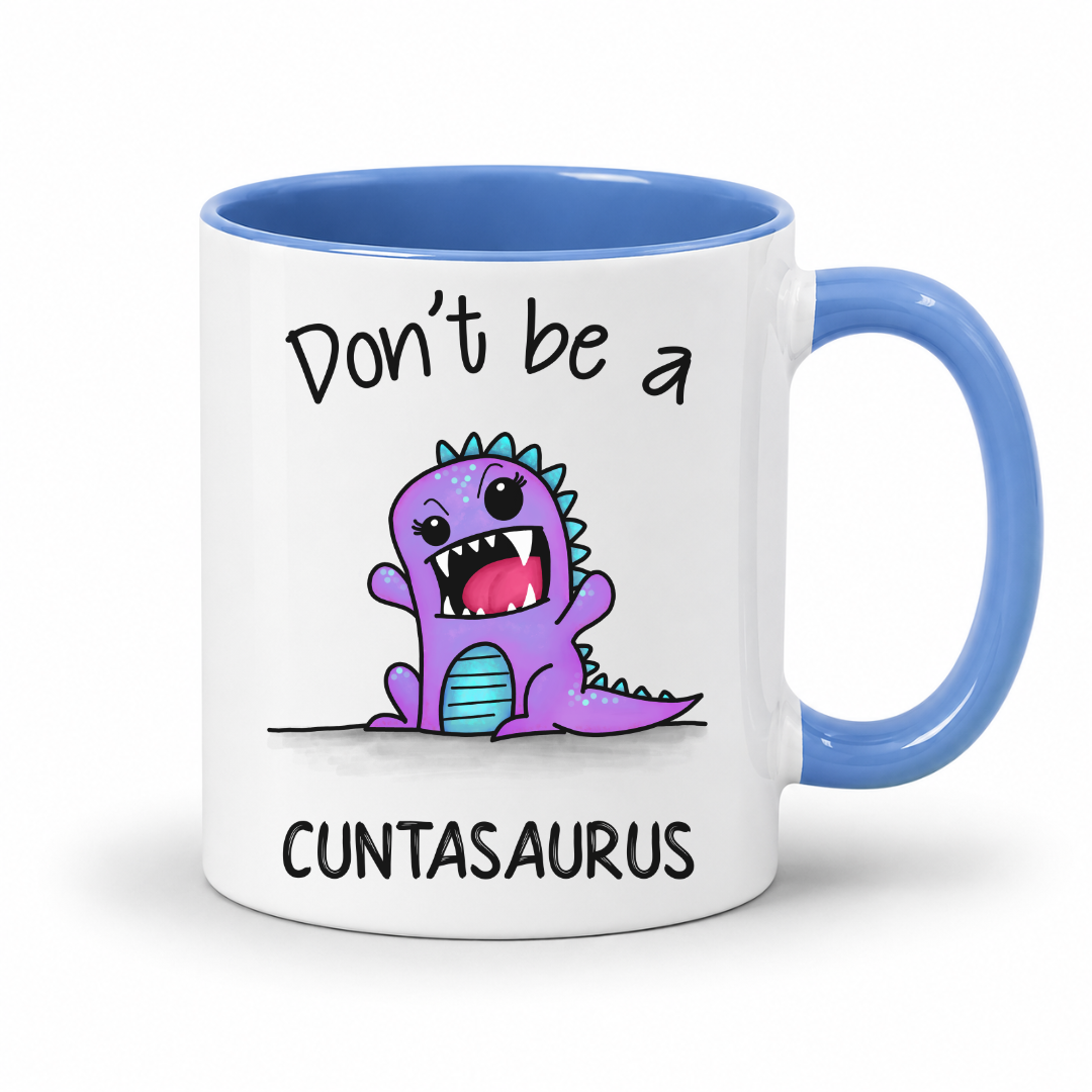 A white ceramic coffee mug with a blue handle and blue interior, featuring a cartoon purple dinosaur graphic and the text 'Don't be a CUNTASAURUS' printed on the front. Grab yours from Coffee and Moo NZ.