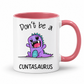 A white ceramic mug with a pink interior and handle, featuring a cute purple cartoon dinosaur and the text 'Don't be a CUNTASaurus' printed on the front. Grab yours from Coffee and Moo NZ.