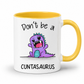 A white ceramic mug with a yellow interior and handle, featuring a cartoon purple dinosaur graphic with the text 'Don't be a CUNTASAUROS' printed on the front. Grab yours from Coffee and Moo NZ.
