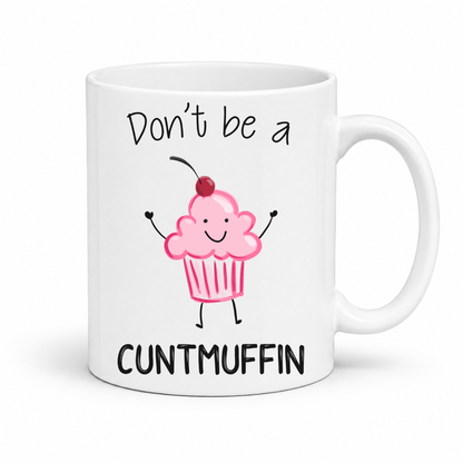 A white ceramic mug with a black handle, featuring a cute pink cupcake illustration with a cherry and the text 'Don't be a CUNTMUFFIN' in black lettering. Grab yours from Coffee and Moo NZ.