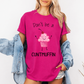 A woman wearing a bright pink graphic t-shirt with a cute pink cupcake character and the text 'Don't be a CUNTMUFFIN' printed on the front, styled with an open light blue denim jacket. Purchase from Coffee and Moo NZ.