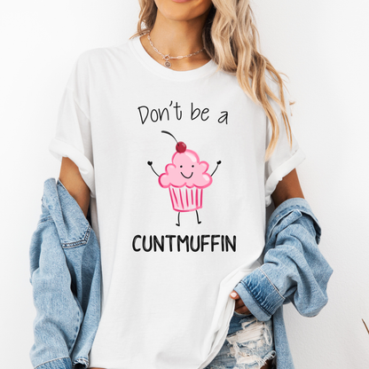A woman wearing a white graphic t-shirt with a pink cupcake illustration and the text 'Don't be a CUNTMUFFIN' in black. She has a light blue denim jacket draped off her shoulders and is wearing distressed jeans against a plain white background. Purchase from Coffee and Moo NZ.