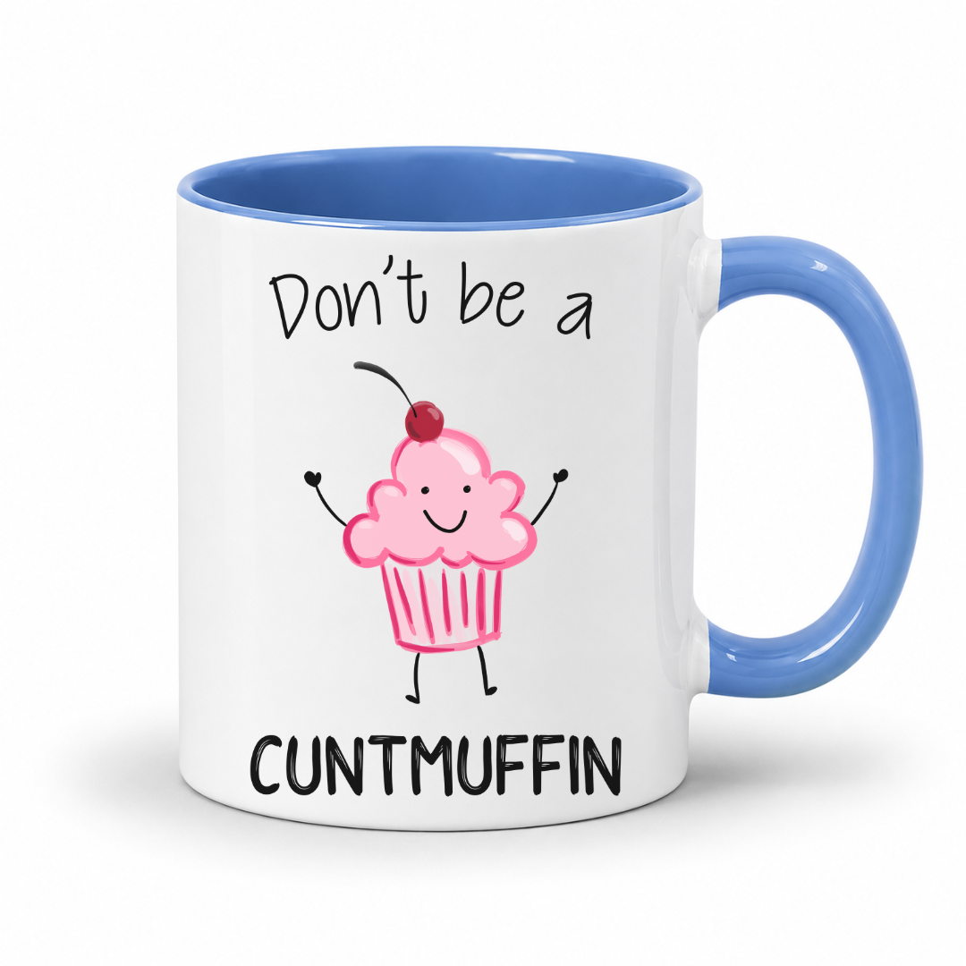 A white ceramic mug with a blue interior, blue handle, and a printed graphic of a smiling pink cupcake with a cherry on top. The text reads 'Don't be a CUNTMUFFIN' in black lettering. Grab yours from Coffee and Moo NZ.