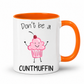 A white ceramic mug with a bright orange handle and interior, featuring a cute pink cupcake graphic with a cherry and the text 'Don't be a CUNTMUFFIN' in black lettering. Grab yours from Coffee and Moo NZ.
