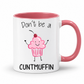 A white ceramic coffee mug with a pink interior and handle, featuring a cartoon cupcake graphic and the text 'Don't be a CUNTMUFFIN' in black lettering. Grab yours from Coffee and Moo NZ.
