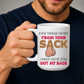 A man in a navy blue t-shirt holds up a white ceramic mug with a humorous graphic. The mug features the text 'EVEN THOUGH I'M NOT FROM YOUR SACK I KNOW YOU'VE STILL GOT MY BACK' in brown and red lettering, with a graphic of hairy balls in the center. Grab yours from Coffee and Moo NZ.