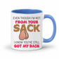 A white ceramic coffee mug with a blue handle and blue interior, featuring a humorous graphic with the text 'EVEN THOUGH I'M NOT FROM YOUR SACK I KNOW YOU'VE STILL GOT MY BACK' and a cartoon graphic of ball bags. Grab yours from Coffee and Moo NZ.