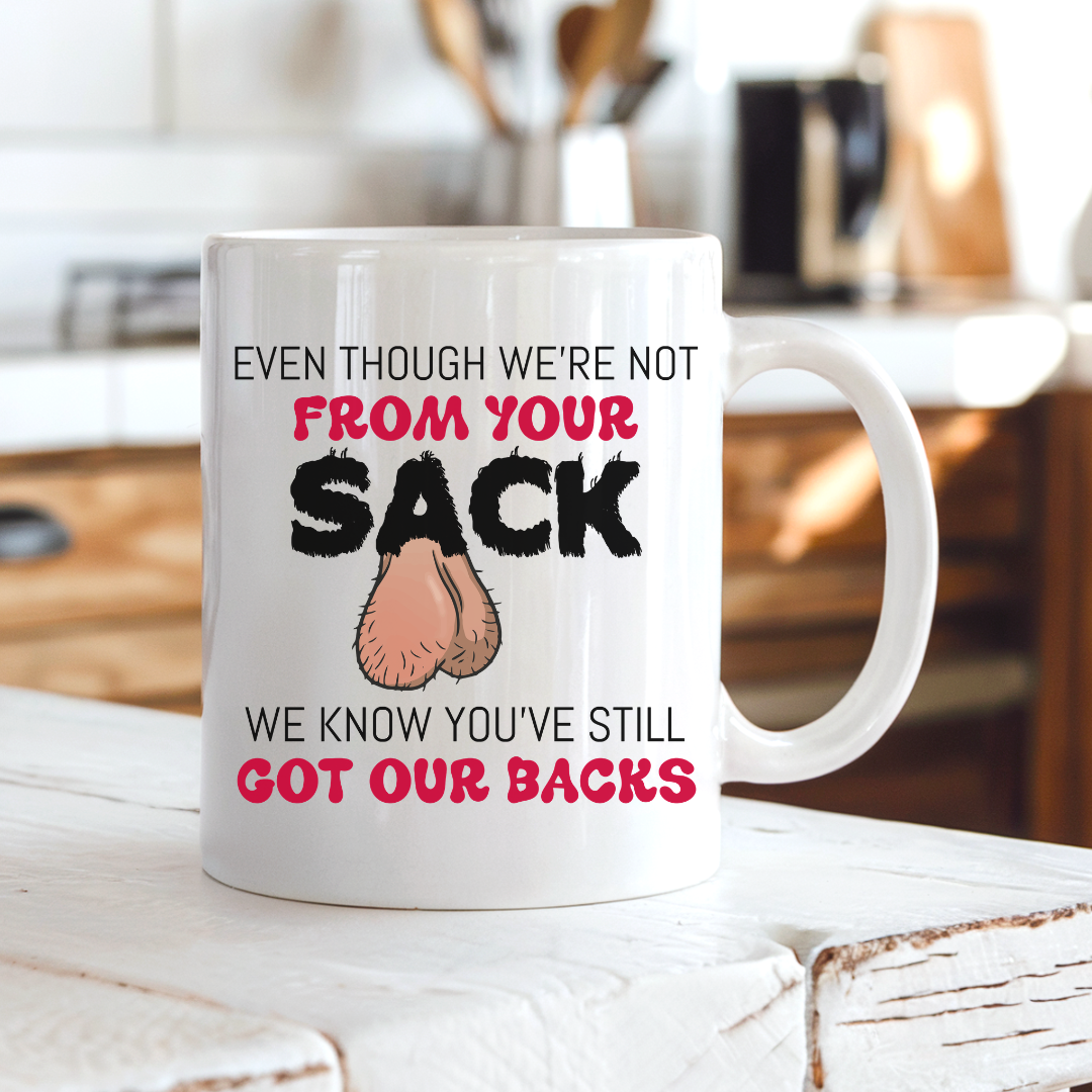 A white ceramic coffee mug with a  humorous graphic. The mug features the text 'EVEN THOUGH WE'RE NOT FROM YOUR SACK WE KNOW YOU'VE STILL GOT OUR BACKS' in black and red lettering, accompanied by a cartoon drawing of a hairy balls. Grab your mug from Coffee and Moo NZ.