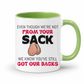 A white ceramic coffee mug with a green interior and handle, has a humorous graphic. The mug features the text 'EVEN THOUGH WE'RE NOT FROM YOUR SACK WE KNOW YOU'VE STILL GOT OUR BACKS' in black and red lettering, accompanied by a cartoon drawing of a hairy balls. Grab your mug from Coffee and Moo NZ.