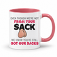A white ceramic coffee mug with a pink interior and handle, has a humorous graphic. The mug features the text 'EVEN THOUGH WE'RE NOT FROM YOUR SACK WE KNOW YOU'VE STILL GOT OUR BACKS' in black and red lettering, accompanied by a cartoon drawing of a hairy balls. Grab your mug from Coffee and Moo NZ.