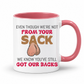 A white ceramic coffee mug with a pink interior and handle, has a humorous graphic. The mug features the text 'EVEN THOUGH WE'RE NOT FROM YOUR SACK WE KNOW YOU'VE STILL GOT OUR BACKS' in brown and red lettering, accompanied by a cartoon drawing of a hairy balls. Grab your mug from Coffee and Moo NZ.
