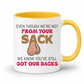 A white ceramic coffee mug with a yellow interior and handle, has a humorous graphic. The mug features the text 'EVEN THOUGH WE'RE NOT FROM YOUR SACK WE KNOW YOU'VE STILL GOT OUR BACKS' in brown and red lettering, accompanied by a cartoon drawing of a hairy balls. Grab your mug from Coffee and Moo NZ.