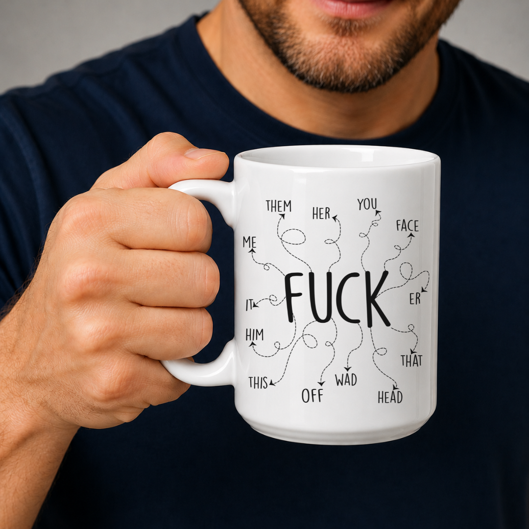A white ceramic mug with black hand-drawn text and doodles, held by a man wearing a navy blue t-shirt against a neutral gray background. From Coffee and Moo NZ.