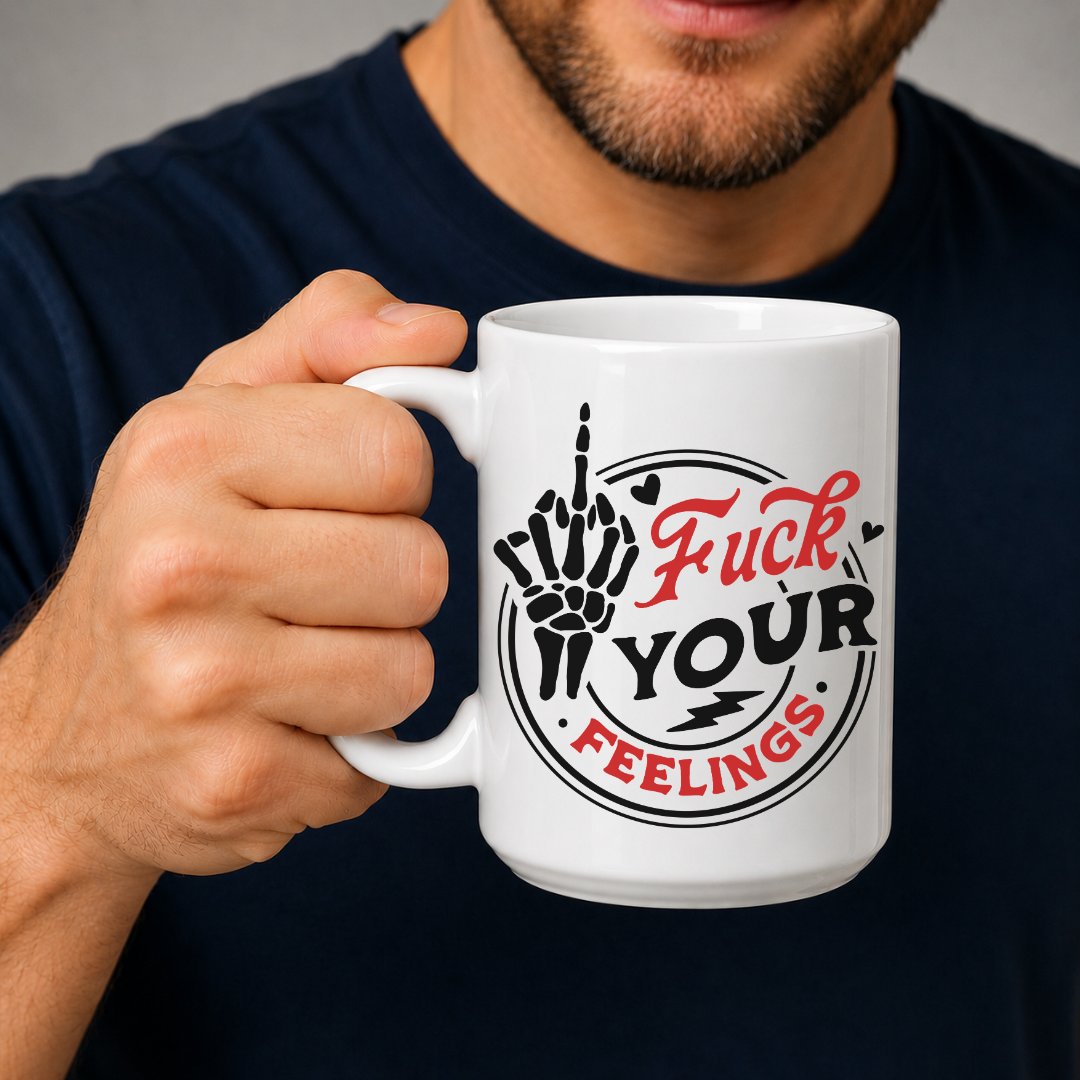 A man in a navy blue shirt holds a white ceramic mug with a graphic design that reads 'Fuck Your Feelings' in red and black text, featuring a hand gesture illustration. Purchase from Coffee and Moo NZ.