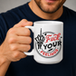 A man in a navy blue shirt holds a white ceramic mug with a graphic design that reads 'Fuck Your Feelings' in red and black text, featuring a hand gesture illustration. Purchase from Coffee and Moo NZ.